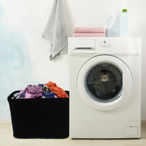 Modern washing machine against blue wall, space for text