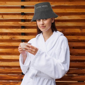 Woman in a bathrobe with a cup of tea on the background of a wall of wooden planks