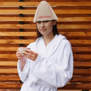 Woman in a bathrobe with a cup of tea on the background of a wall of wooden planks